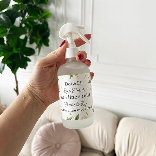 Hand holding a bottle of Dot & Lil rice flower air linen mist against a neutral background